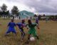 Soccer match at Tloma Primary School. Two boys contesting for ball as teammates look on